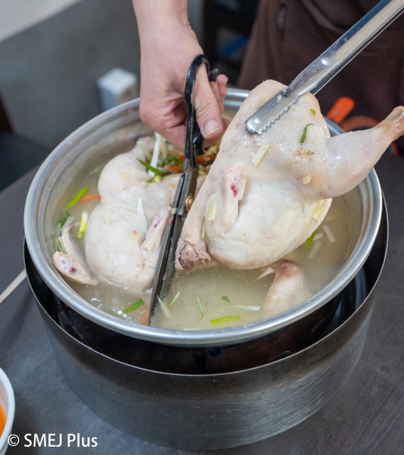 鍋の鶏肉をカットする写真