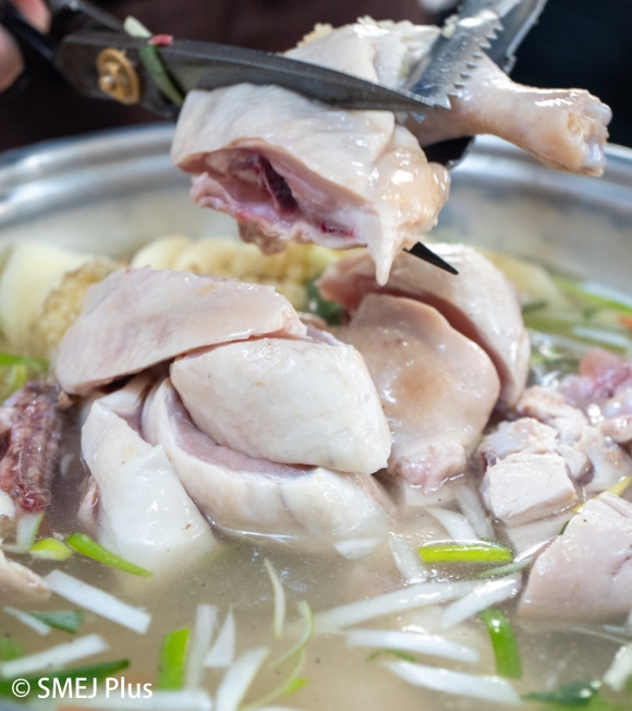鍋の鶏肉をカットする写真